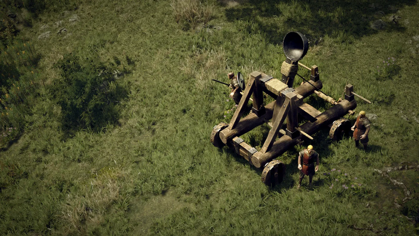 Une catapulte de bois dans une prairie, servie par trois hommes